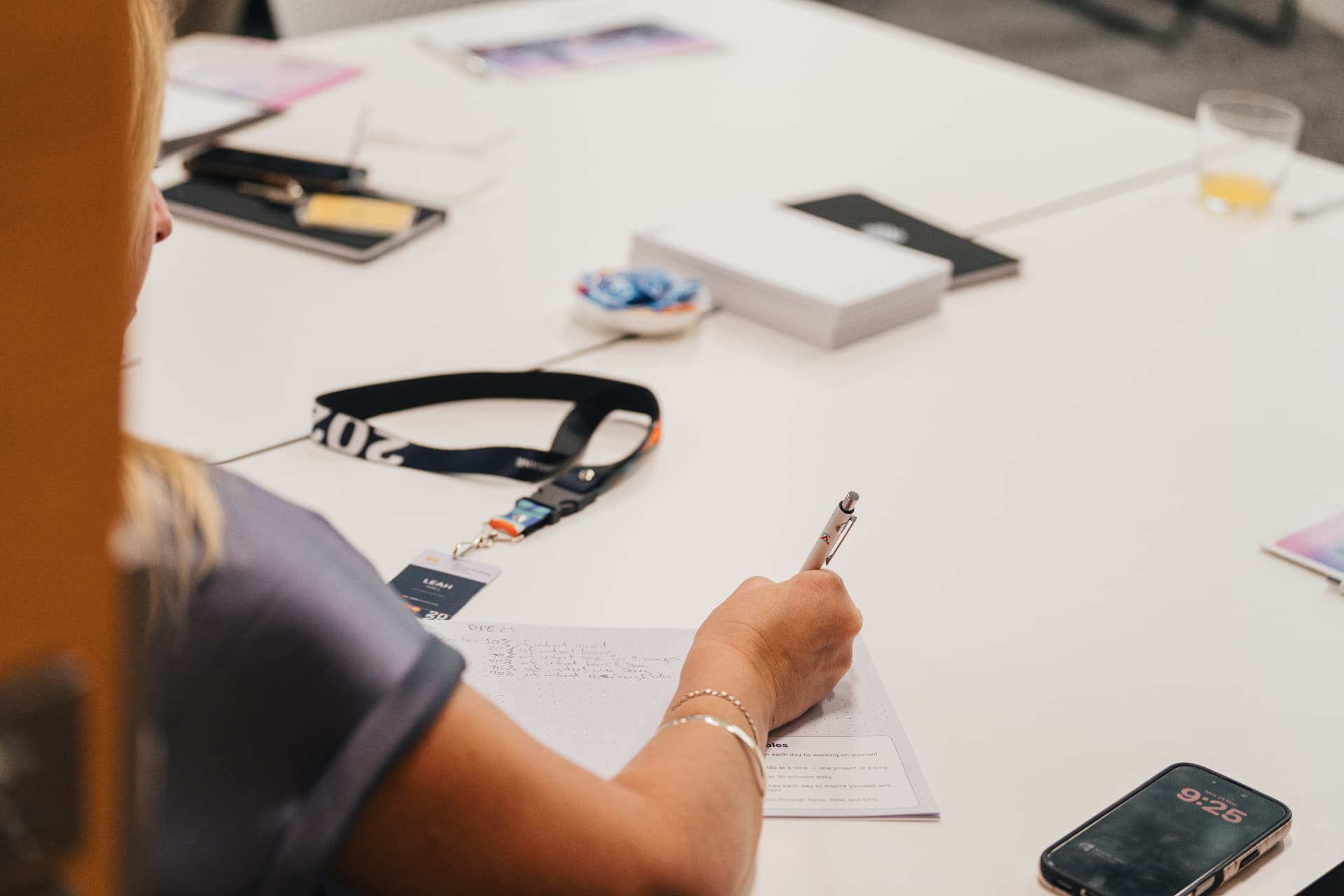 An attendee writing notes in a workbook at a Wize workshop table