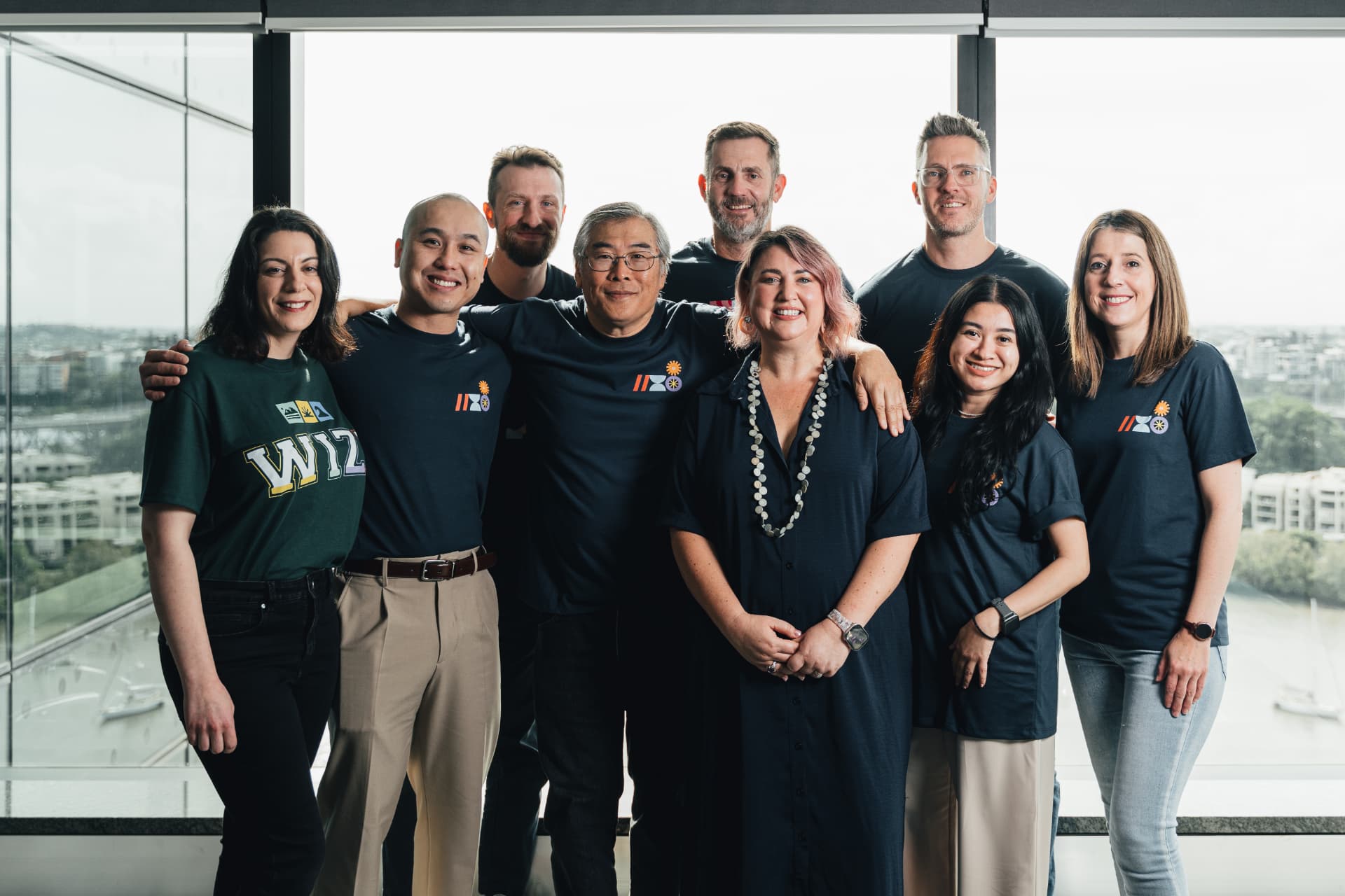 The Wize team standing together in front of a window overlooking the water