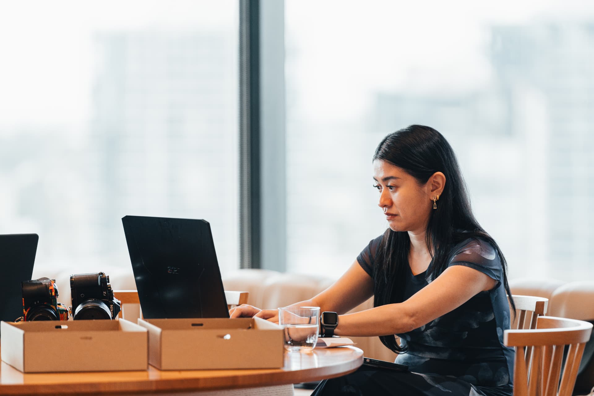 An attendee working on a laptop at a round wooden table during a Wize workshop